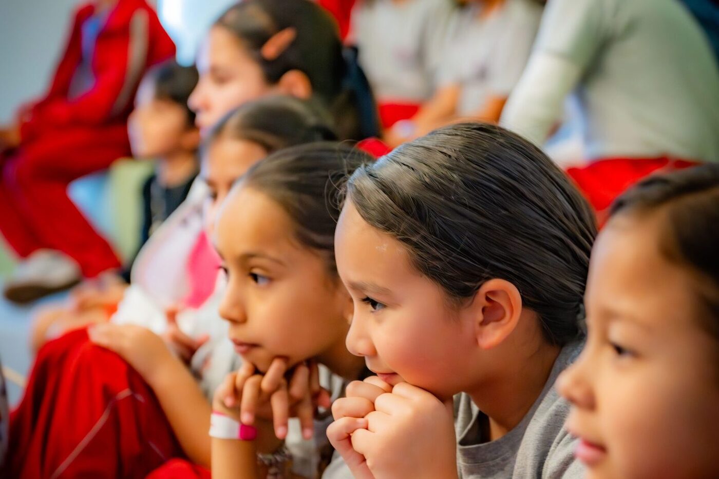Alumnas del Colegio Marcelina, sentadas en fila y con la barbilla apoyada en las manos, escuchando con atención.